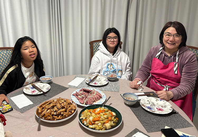 同學與寄宿家庭成員圍坐餐桌前享用晚餐,桌上擺滿中式家常菜餚,氣氛溫馨愉快 | 澳洲遊學團