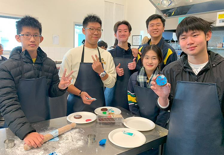 同學在廚藝教室中學習烘焙與裝飾甜點,手拿成品微笑合照 | 澳洲遊學團