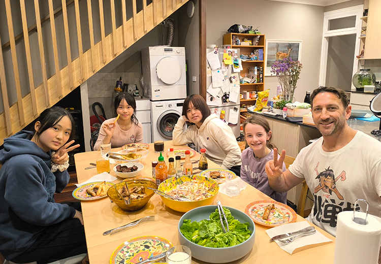 同學與外籍寄宿家庭成員圍坐餐桌共享晚餐,桌上擺滿豐盛食物,氣氛溫馨自然 | 澳洲遊學團