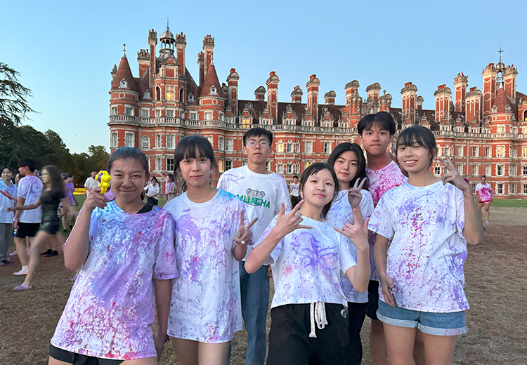 同學穿著被顏料染色的白T恤,笑容滿面地擺出勝利手勢,享受色彩活動的歡樂氛圍 | 英國遊學團