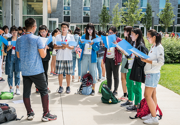 同學於加拿大大學校園中進行戶外學習活動,專注朗讀教材,展現沉浸式學術體驗的真實一刻 | 加拿大遊學團